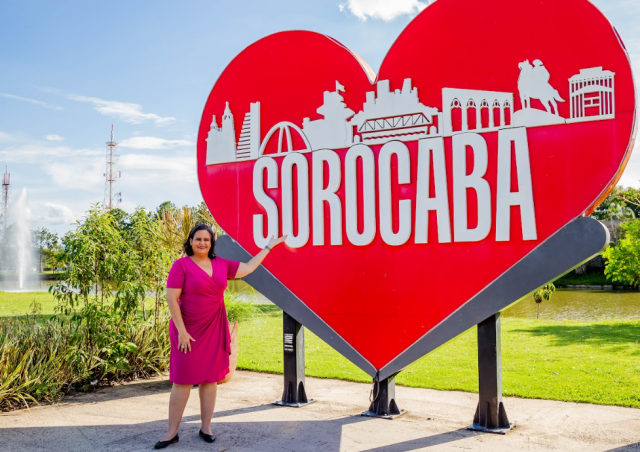 Manu Barros ao lado do letreiro de Sorocaba